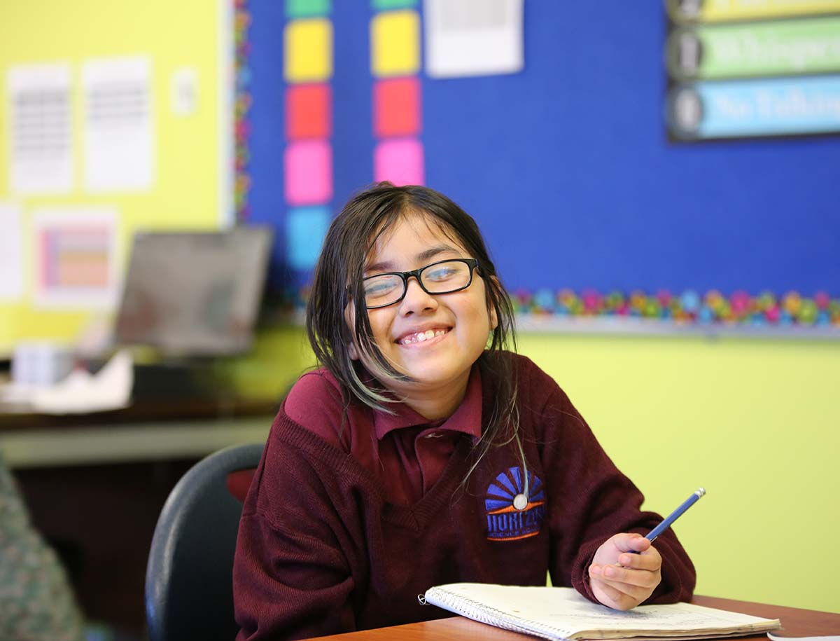 Elementary student smiling and posing together in a classroom.